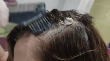 Genç bir kadın saçını boyuyor.