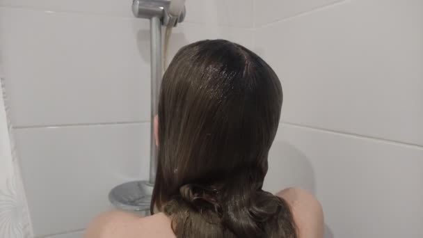 若いです魅力的な女性とともに長い髪洗浄彼女の頭でシャンプーとともにザシャワー — ストック動画