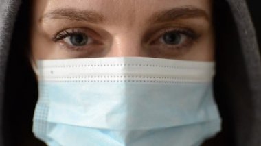 Siyah arka planda izole edilmiş tıbbi maske takan kapüşonlu genç bir kadın.