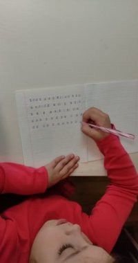 Dikey video. Küçük kız ödev yapıyor, mektup yazmayı öğreniyor.