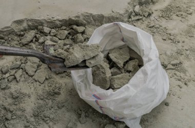 İnşaatçı, inşaat atıklarını kürekle torbaya koyar.