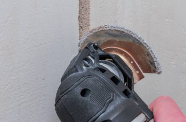 İnşaat işçisi, elektrik kablolarını yenilemek için duvarda bir delik açıyor.