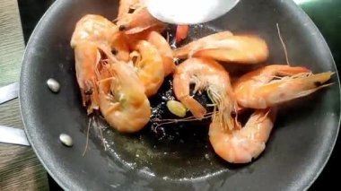 Şef tavada karides kızartıyor.
