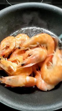 Şef tavada karides kızartıyor.