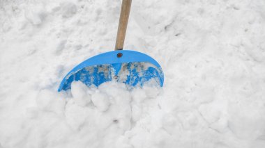 Kasırgadan sonra yolları temizledikten sonra kar yığınında kar temizleyen mavi bir kürek.