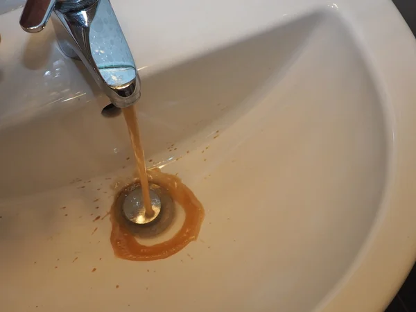 Polluted brown water flowing into the bathroom sink — Stock Photo, Image