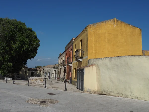 Plaza mediterránea con casas de colores pastel y un árbol verde — Foto de Stock