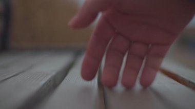 Çok yakın plan. Çerçevede bir el beliriyor. Odaklanıyor ve tekrar bulanıklaşıyor..
