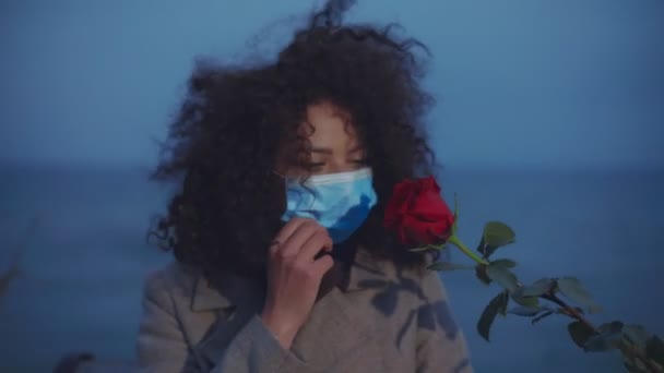 Крупним планом дівчина знімає медичну маску і обнюхує троянду. Вона не пахне трояндою — стокове відео