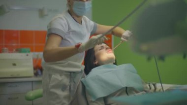 Kadın doktor dişçi hastaların ağzını yıkar.