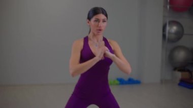 Formda kız yan taraflarda çömelme hareketleri yapıyor.