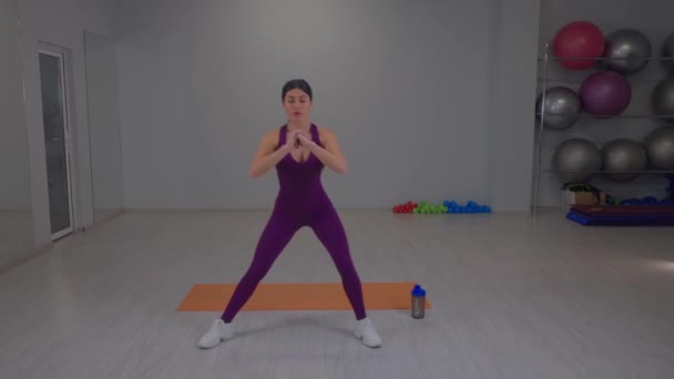 Fit girl performs side squats on the sides — Wideo stockowe