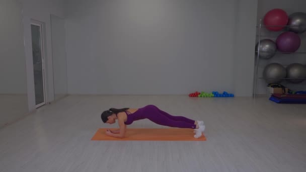 Fit girl performs a plank exercise — Wideo stockowe