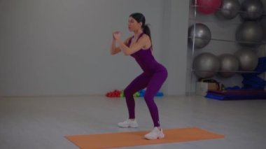 Atletik kız titreşimli çömelme hareketleri yapıyor.