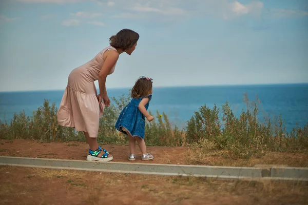 Vrouw en kind kijken elkaar aan tegen de achtergrond van de zee — Stockfoto