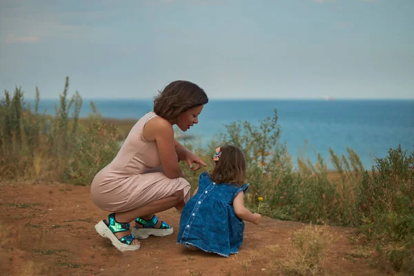 Vrouw en kind kijken elkaar aan tegen de achtergrond van de zee — Stockfoto