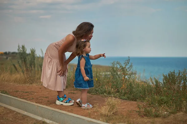 Moeder wijst haar hand naar haar dochtertje naar de horizon — Stockfoto