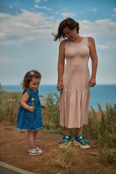 Vrouw loopt met haar dochtertje in een weiland — Stockfoto