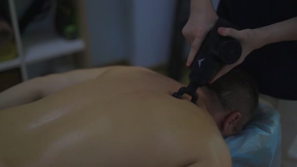 Yakın çekim erkek masaj terapisti masaj odasında loş ışıklı bir adama sırt masajı yapıyor. — Stok video