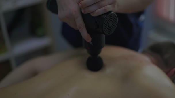Крупним планом чоловічий масажист робить масаж спини чоловікові в масажному кабінеті з тьмяними вогнями Низький ключ — стокове відео