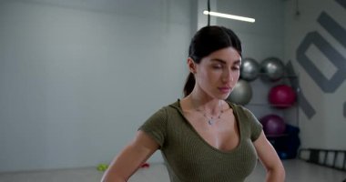 Fitness stüdyosunda atletik bir kadın, egzersiz rutininin bir parçası olarak boynunun esnekliğini ve gücünü arttırmak için başını öne ve arkaya eğiyor..