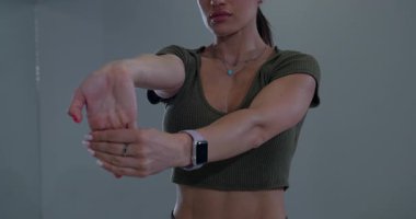 Kadın bir spor salonunda bilek ve kollarını esnetiyor. Esnekliği arttırmak ve gevşemeyi teşvik etmek için esnerken duruşuna ve nefesine odaklanıyor..