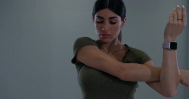 Modern bir spor salonunda atletik kadınlar omuzlarını uzatır. Akşamki antrenmanında esnek ve güçlü olmaya odaklanıyor. Sağlık ve zindeliği teşvik ediyor..