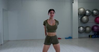 Atletik kadın, elleri sımsıkı bağlı bir şekilde öne eğiliyor. Duruşu antrenman sırasında güç ve esneklik gösteriyor..