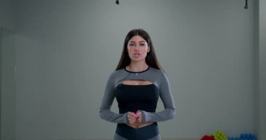 Atletik bayan spiker kameraya modern bir spor salonuna özgüvenle sesleniyor. fitness ipuçları ve rehberlik sunarken meşgul görünüyor..