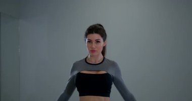 Atletik bir kadın kapalı bir alanda kol dairesi egzersizi yapıyor. Formda olduğu sürece gücünü ve esnekliğini arttırmak için hareketlerine odaklanıyor..