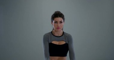 Atletik bir kadın içeride duruyor ve odaklanarak kol daireleri çiziyor. Formunun bir parçası olarak esnekliğini ve gücünü arttırmak için bu egzersizi yapıyor..