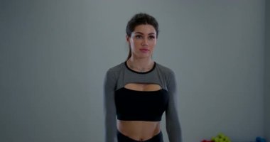 Atletik bir kadın, kapalı bir spor salonunda kol daireleri çizerken odaklanmış ve meşgul olur. Sahne, onun formda ve güçlü olmaya olan bağlılığını yakalıyor..