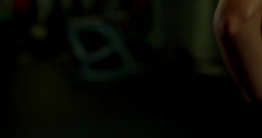 Gevşek saçlı genç bir kadın, iyi aydınlatılmış bir spor salonunda ayakta esneme hareketi yapıyor. Antrenman, onun esnekliğini vurgulayarak ve fitness üzerine yoğunlaşarak sabah gerçekleşir..