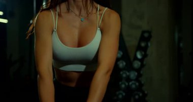 Saçları dökülmüş genç bir kadın bir kettlebell salıncak gösterisi yapıyor. Bacakları ve göbeğiyle uğraşırken odaklanma ve gücünü koruyor. Egzersiz onun kendini adadığını ve formda olduğunu gösteriyor..