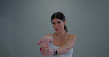 Formda olan sporcu kadın, antrenmandan önce ellerini ısıtıyor, Flexörleri bilek esnetiyor, egzersiz yapıyor.