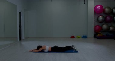 Atletik bayan dinlenme pozisyonu zemin eğitimi geniş oda spor ekipmanları arka planı