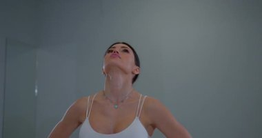 Esmer kadın ellerini kalçasında tutuyor. Geleceğin başarısını hayal ederek yükseğe bakıyor.