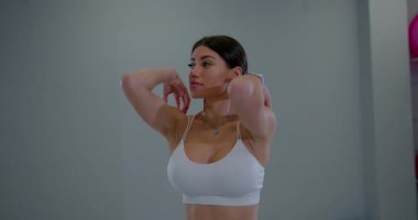 Eğitimden önce modern spor merkezinde omuzlarını esneten odaklanmış bir kız.