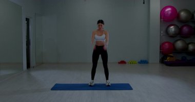 Sportif Kadın Kolları Isınıyor Mavi Yoga Mat 'ın üzerinde İçi Boş Spor Salonu Stüdyosunda