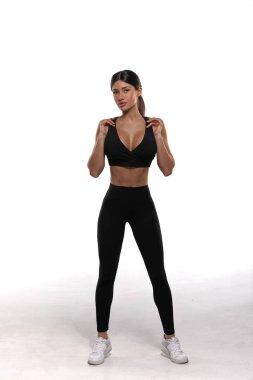 Genç bir atlet kız atletizm kıyafetlerini giyerek parlak bir stüdyoda fitness seansına hazırlanıyor. Çalışmalarına odaklanıyor ve azim ve güç gösteriyor..