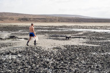Bir adam çamurdan sonra çamurdan gölde yürür. Tıbbi tedavi çamuru.