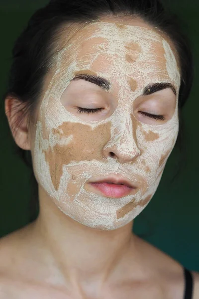 Young brunette woman with a clay homemade mask on her face with her eyes closed — Stock Photo, Image