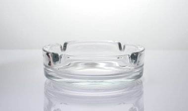 Parlak ışık arkaplanındaki şeffaf cam kül tablası.