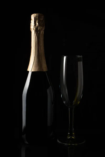 Una botella de champán y una copa sobre un fondo negro. — Foto de Stock