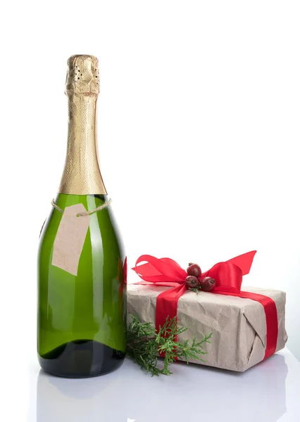 A bottle of alcohol and a gift on a light background. — Stock Photo, Image