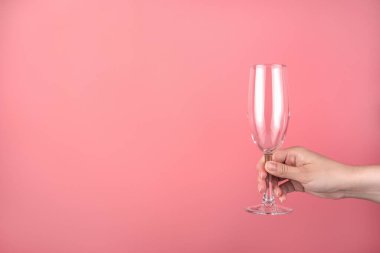 Elinde pembe arka planda boş bir şampanya bardağı var..