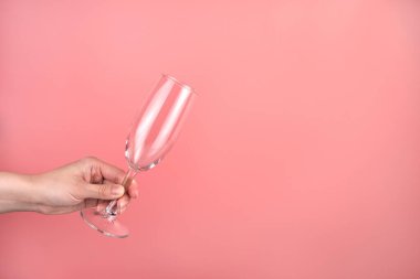 Pembe arka planda bir kadının elinde şampanya bardağı..