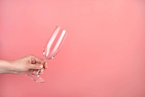 Copa de champán en la mano de una mujer sobre un fondo rosa. — Foto de Stock