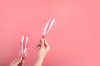 Bir kadının ellerinde pembe arka planda şarap kadehleri..