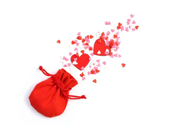 Fireworks from hearts of different shapes fly out of a red bag on a light background. — Stock Photo, Image